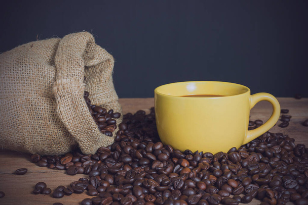 Xícara de café e grãos de café em mesa de madeira com fundo preto. espaço de cópia para o estilo vintage texto
. - Foto, Imagem