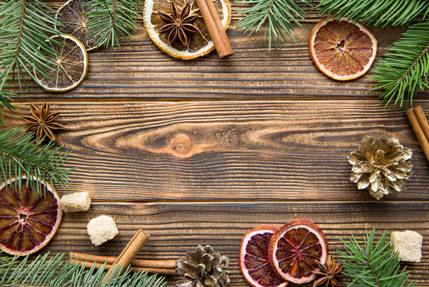 Tranches d'oranges séchées, pommes de pin dorées et branches de sapin sur table en bois marron. Espace pour le texte
.  - Photo, image