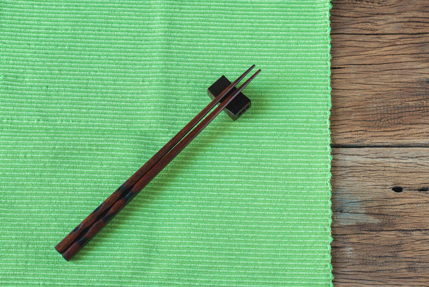 Chopsticks with green tablecloth on the table wood. Top view with copy space for text. - Photo, Image
