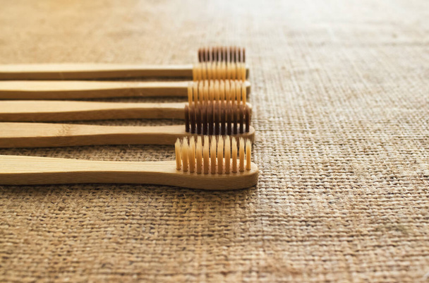 Набор натуральных бамбуковых зубных щёток на деревенском фоне с копировальным пространством. Устойчивый образ жизни и пластиковая свободная концепция, нулевые потери дома. Необходимое для ванной комнаты
 - Фото, изображение