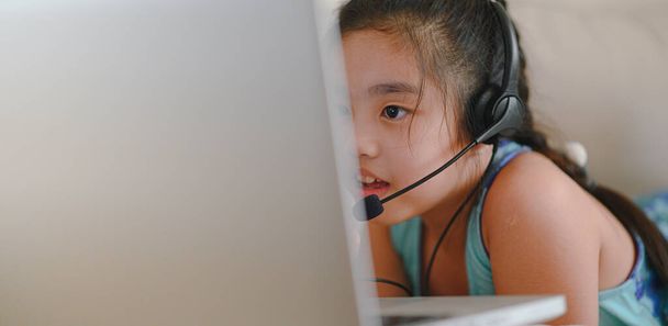 asiatique fille étudiant porter casque regarder webinaire écouter cours en ligne communiquer par conférence vidéo appel. . L'enseignement à domicile et à distance, en ligne, Internet protègent contre les virus COVID-19
.  - Photo, image