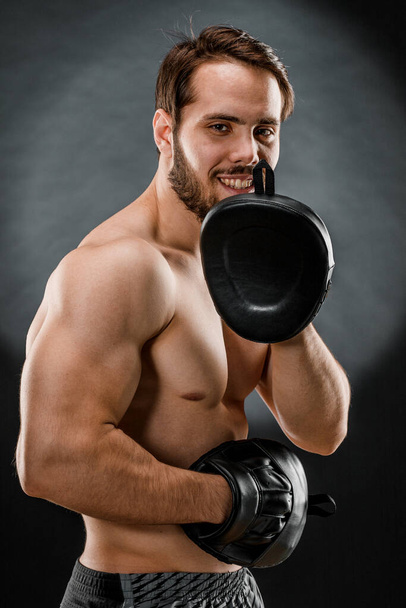 Il pugile è un combattente, che guarda con rabbia la macchina fotografica. Giovane modello di fitness maschile caucasico isolato su sfondo nero. - Foto, immagini