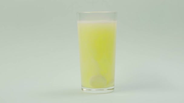 Pigułka wpada do szklanki z wodą. musująca tabletka aspiryna. Terminy - Materiał filmowy, wideo