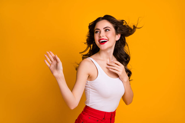 Photo of funny pretty lady hairdo flight satisfied look side empty space warm summer breeze waving arm friends wear white casual singlet red skirt isolated yellow color background - Φωτογραφία, εικόνα