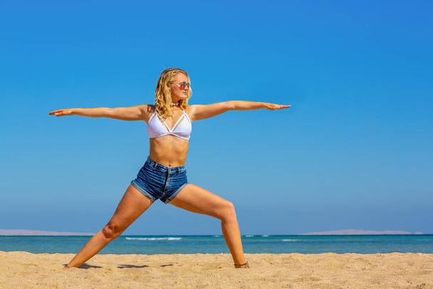 Blonde caucasian woman practicing yoga postures on egyptian beach - Foto, Imagen