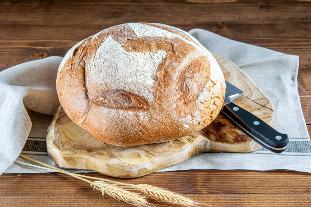 Integrál kenyér, búzapecsenyék a fa vágódeszkán, kés és szalvéta a fa asztalon. Egészséges táplálkozás beépített kenyér.  - Fotó, kép