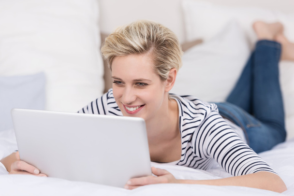 Woman smiling as she reads her tablet - Zdjęcie, obraz