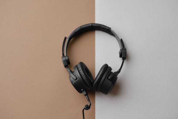 Flat lay composition with black studio headphones  on brown background, podcasting concept. - Fotó, kép