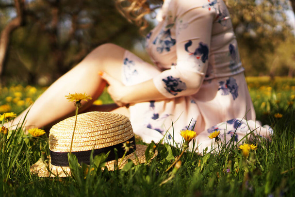 Mulher com um chapéu de palha num campo de flores. Foco no chapéu
 - Foto, Imagem