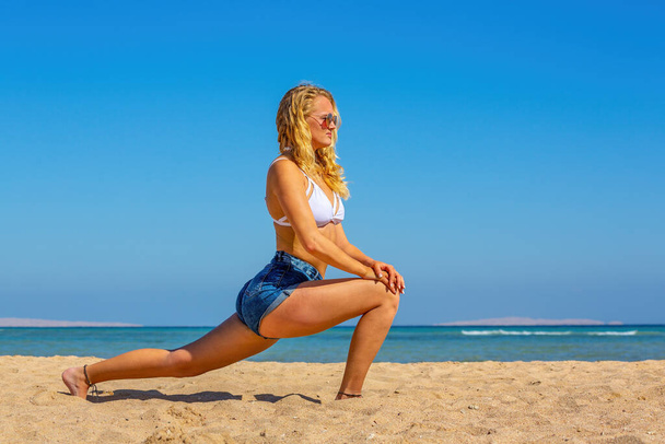 Young european woman in yoga position on egyptian beach - Photo, Image