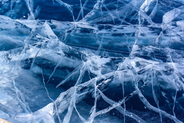 Sok gyönyörű repedés a tiszta kék jégen. Rétegelt vastag jég. Vízszintes. - Fotó, kép