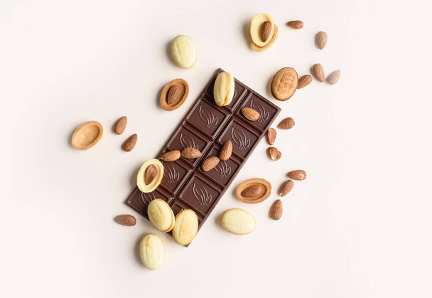Na lehkém pozadí je čokoládová tyčinka s mandlemi, vlašskými ořechy, ořechy s vařeným kondenzovaným mlékem. Pohled shora, místo pro text. Plocha - Fotografie, Obrázek