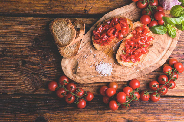 Italian bruschetta, toasted bred with fresh tomato and basil on woody vintage table - Foto, Bild
