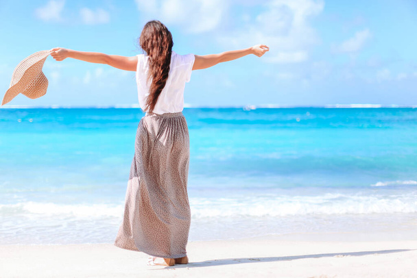 熱帯の海岸で楽しんでいる若い美しい女性。カリブ海の島で青い空とターコイズブルーの海を背景に幸せな女の子 - 写真・画像
