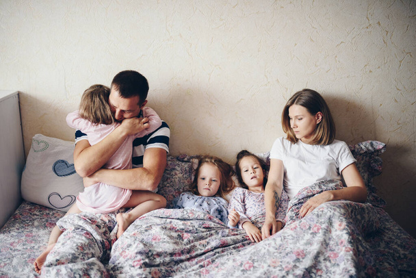 Children and parents rest in the morning in bed. Children indulge, hug. Twins. Three daughters. - Photo, image