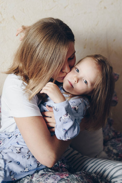 Mom hugs and kisses daughter. - Zdjęcie, obraz