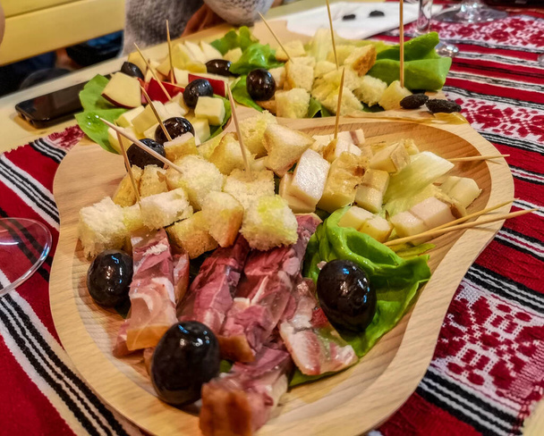 Деревенское блюдо с мясным ассорти: ветчина, сыр, оливки и другие традиционные блюда из пальца, обычная румынская закуска на деревянной тарелке
 - Фото, изображение