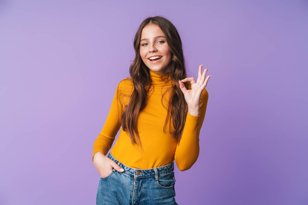 Image of young beautiful woman with long brown hair smiling and gesturing okay sign isolated over violet background - Foto, Imagen