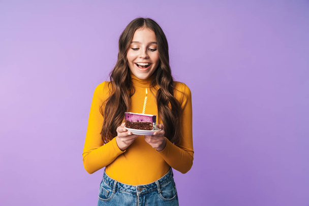 Kép fiatal gyönyörű nő hosszú barna haj mosolygós és gazdaság születésnapi torta elszigetelt felett lila háttér - Fotó, kép