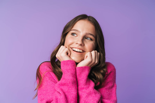 Image of young beautiful woman with long brown hair smiling and touching her face isolated over violet background - Фото, изображение