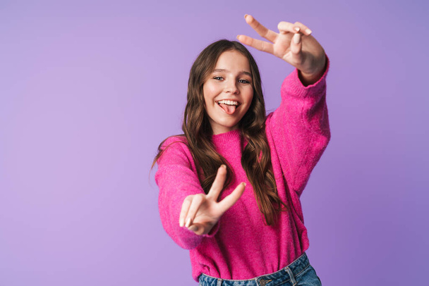 Image of young beautiful woman with long brown hair smiling and gesturing peace fingers isolated over violet background - Valokuva, kuva