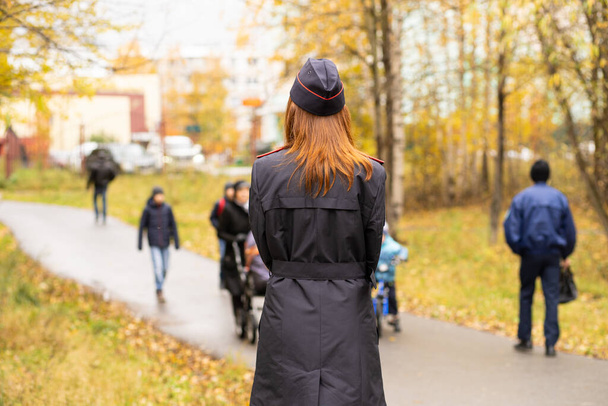 Mujer policía de pie con la espalda en uniforme negro
 - Foto, imagen