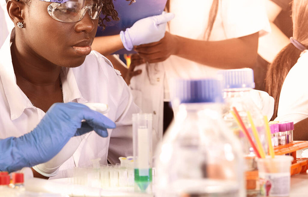 Studenti di medicina africana, giovani laureati in laboratorio di ricerca o laboratorio di test medici che eseguono vari test su campioni.Ricercatrice donna fa analisi pcr amplificare il DNA con pipetta automatica - Foto, immagini