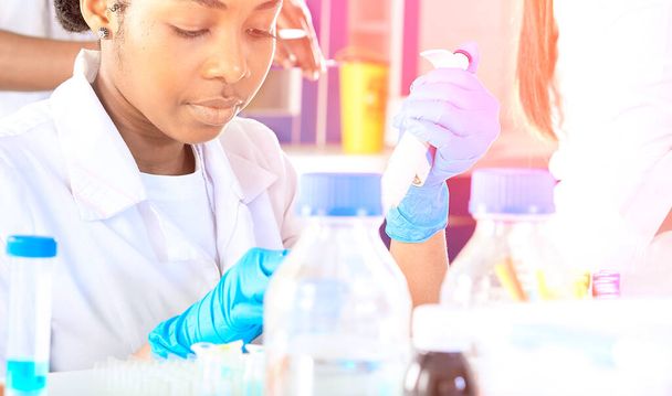 Female African medical students, young graduates in research laboratory or medical test lab performing various testing on samples.Ongoing nucleic acid pcr test for sars-cov-2 corona virus. - Foto, Imagen