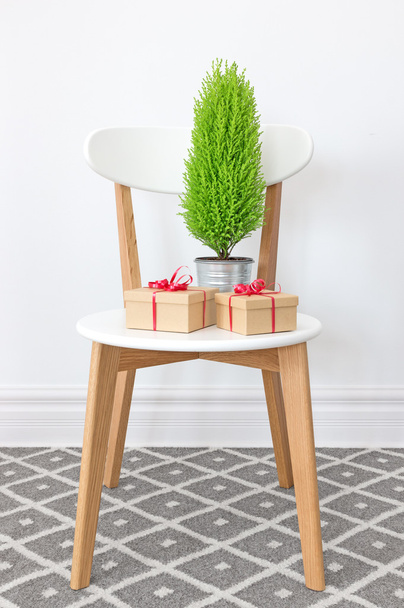 Cadeaux et petit arbre vert sur une chaise blanche
 - Photo, image