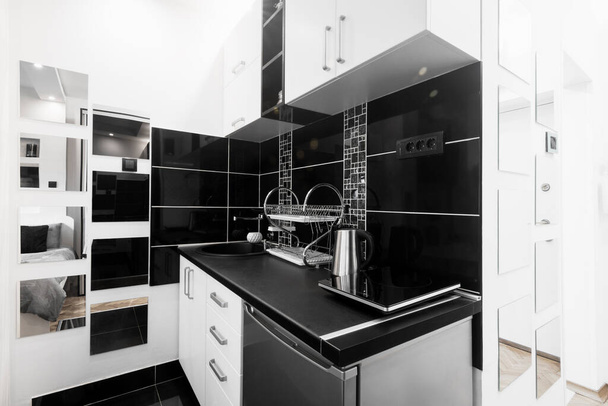 Černá a bílá kuchyně s novým nábytkem, moderní design interiéru v apartmánu. - Fotografie, Obrázek