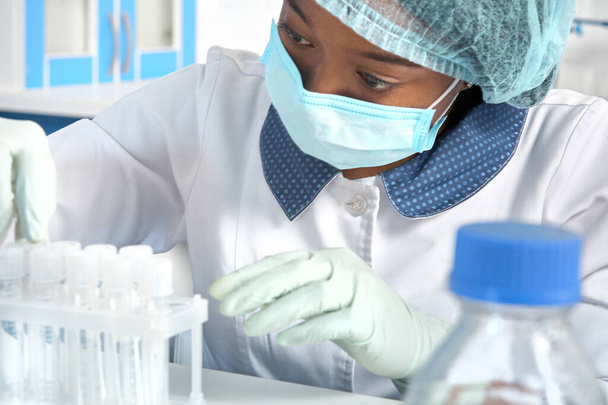 Técnica femenina africana, asistente técnica, trabajo con hisopos bucales, muestras de pacientes para detección de Covid-19, coronavirus novedoso SARS-CoV-2. Laboratorio de pruebas médicas, laboratorio, centro de pruebas interior. - Foto, Imagen