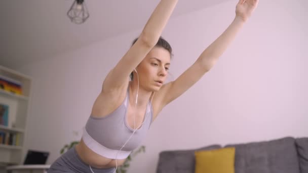 Niski kąt widzenia energicznej kobiety jogi rozciągającej ramiona, ćwiczącej w domu - Materiał filmowy, wideo