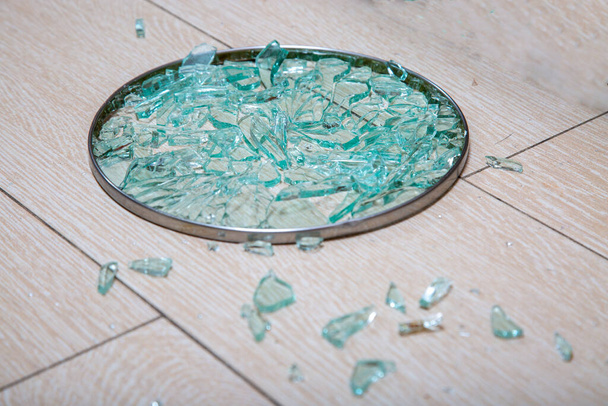 Eine Nahaufnahme eines zerbrochenen Glasdeckels liegt auf einem Pfahl aus Fliesen. Glasscherben glänzen. Weicher Fokus, Seitenansicht - Foto, Bild