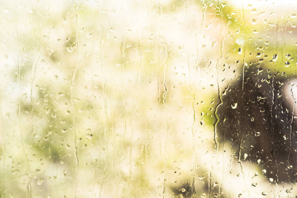 Gocce di pioggia estive sulla finestra dopo un acquazzone con un temporale. Giornata di sole con gocce d'acqua sul vetro. Il concetto di miglioramento del tempo
. - Foto, immagini