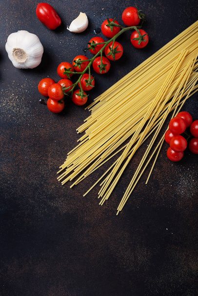 İtalyan makarnası pişirmek için gerekenler: spagetti, domates ve siyah masada sarımsak. Fotokopi alanı olan en üst görüntü - Fotoğraf, Görsel