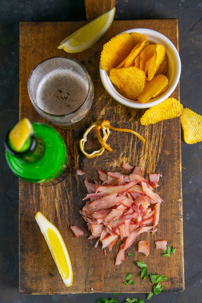 Crab rings with beer, lemon and potato chips on dark wooden board. Snack on fish with beer. Close-up. - Photo, image