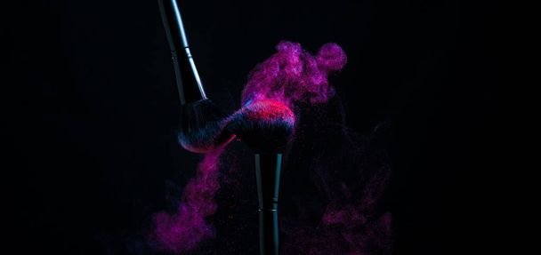 Make up brushes with red and blue powder a black background - Foto, imagen