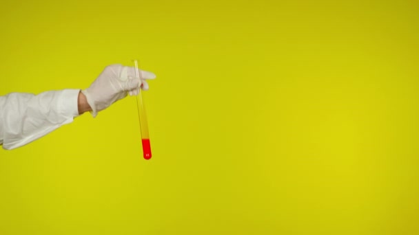 Hand in Hand in Mantel und Handschuhschutz zeigen Glasröhre mit der roten Substanz - Filmmaterial, Video