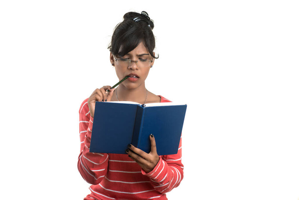Pretty young girl holding book and posing on white background - Foto, afbeelding