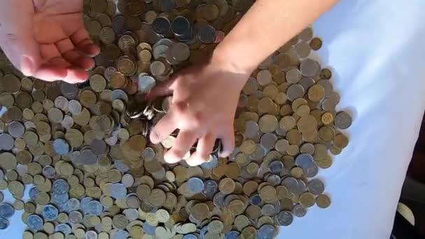 Osoba dwie ręce grabi monety na stole i wylewa się z garstki na powierzchnię - Materiał filmowy, wideo