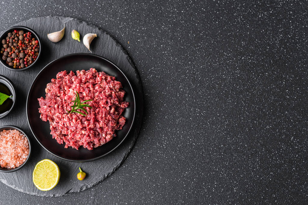 Carne picada fresca carne molida en un plato negro sobre fondo de piedra
. - Foto, Imagen