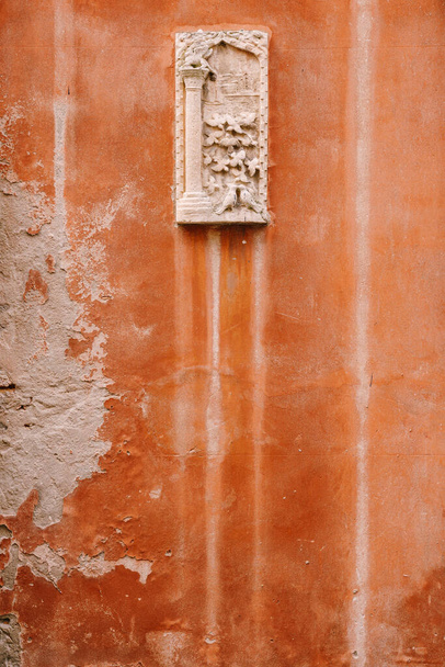 Detailní záběry fasád budov v Benátkách, Itálie. Kamenný basreliéf na malém kamenném obdélníkovém prkně, na oranžové stěně na fasádě budovy. - Fotografie, Obrázek