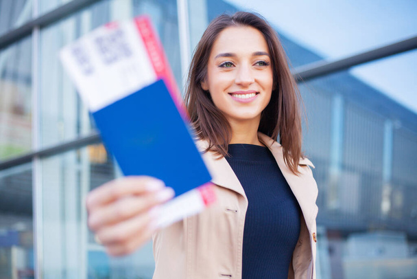 Woman near the airport holding a passport and plane tickets - Fotoğraf, Görsel