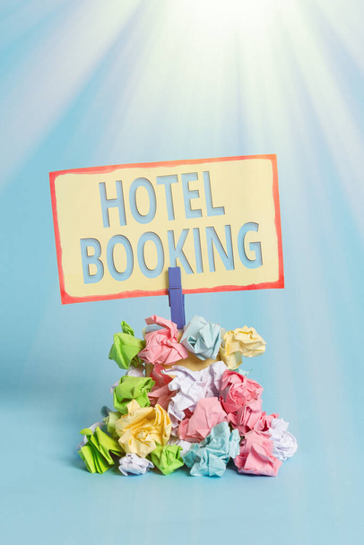 Szöveges tábla a Hotel Booking-ról. Konceptuális fotó Online foglalás Elnöki lakosztály De Luxe Vendéglátás Emlékeztető halom színes gyűrött papír ruhacsap emlékeztető kék háttér. - Fotó, kép