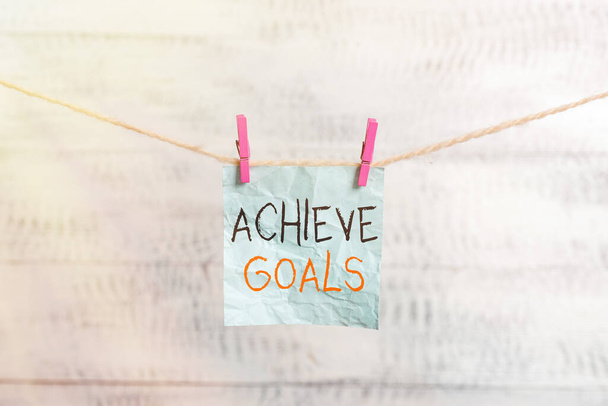 Writing note showing Achieve Goals. Business photo showcasing Results oriented Reach Target Effective Planning Succeed Clothesline clothespin rectangle shaped paper reminder white wood desk. - Photo, Image