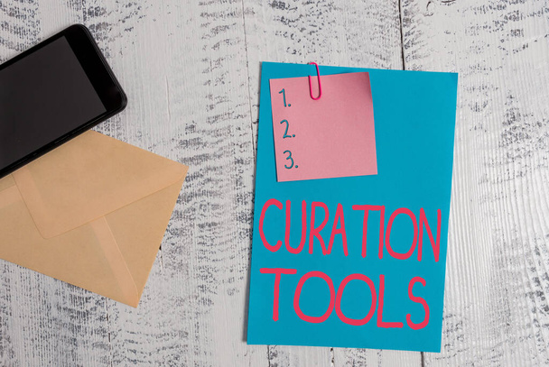 Text sign showing Curation Tools. Conceptual photo Software used in gathering information relevant to a topic Envelope blank sheet paper sticky note smartphone wooden vintage background. - Photo, Image