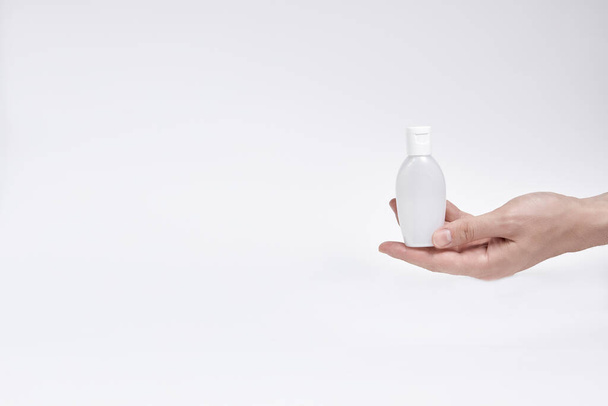 a small bottle for cream, liquid or antiseptic in the hand on a white background. copyspace - Foto, afbeelding