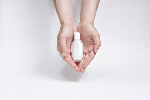 une petite bouteille pour crème, liquide ou antiseptique à deux mains sur fond blanc. copyspace
 - Photo, image