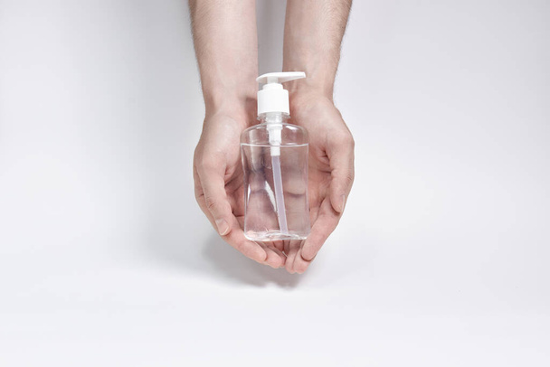 a small bottle for cream, liquid or antiseptic in two hands on a white background. copyspace - Foto, afbeelding