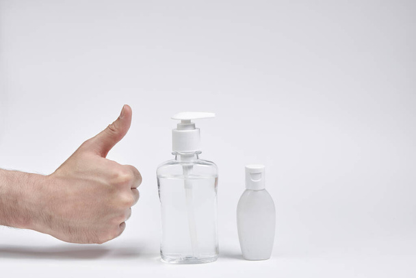 hand with thumb up or like together with a bottle or container for liquid, cream or antiseptic on a white background - Foto, afbeelding
